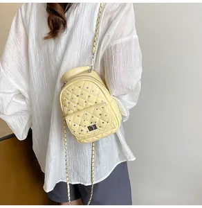 Detail of light yellow quilted mini backpack with silver rivets and metal chain strap