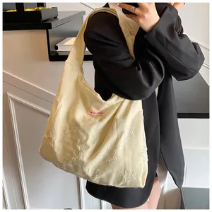 Detail of light yellow canvas tote bag with textured plush stars and pink woven label