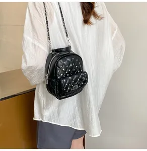 Model wearing a black quilted mini backpack with sparkling silver rhinestones and chain strap