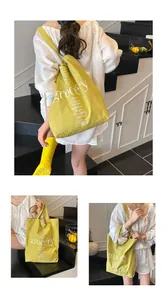 Detalle del bolso tote de lona verde con texto blanco y diseño gráfico
