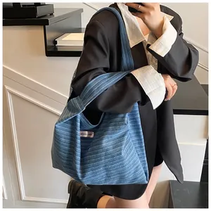 Detailed macro view of the blue striped fabric texture and the logo label on the tote bag
