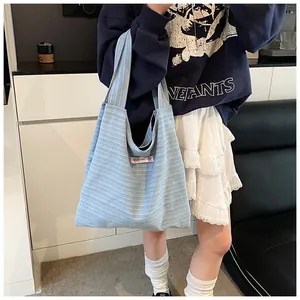 Detail of light blue striped canvas tote bag with pink heart patch and embroidered text
