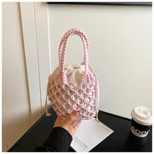 Détail du sac seau rose tissé main avec doublure blanche à cordon et texture en tricot