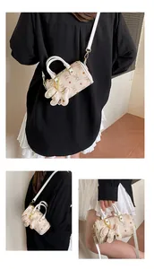 Detailed views of a mini cream Boston bag featuring bear monogram and bear charm accessory