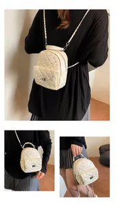Detail view of quilted cream backpack with silver studs and chain straps shown on a model