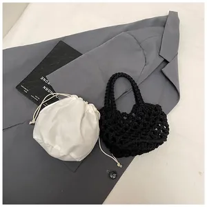 Détail du sac cabas au crochet noir avec pochette intérieure blanche à cordon sur tissu gris