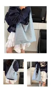 Detailed view of blue and white striped canvas tote bag with pink label and wide shoulder strap