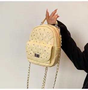 Detail of yellow quilted mini backpack with rhinestone studs and silver chain strap