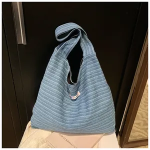 Detail of blue pleated knit tote bag with striped texture and pink label on top