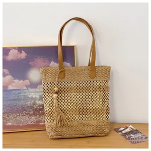 Detailed view of handmade woven straw tote bag with elegant tassel and leather handle