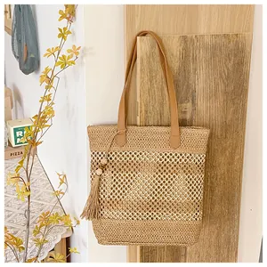 Detail of hollow-out straw tote with leather handles and tassel accent for beach vacation