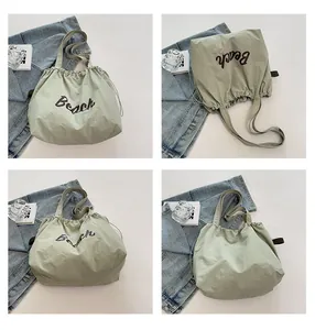 Detalle de bolso de hombro de nailon verde claro con estampado Beach y cordón ajustable