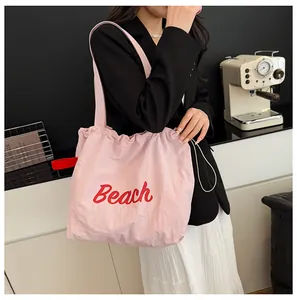 Detalle de bolso tote de nailon rosa con cordón y estampado Beach rojo con tiras largas