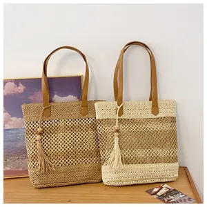 Detail of hollow woven straw tote bags with faux leather handles and wooden bead tassels