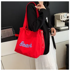 Detalle del bolso tote de nailon rojo con estampado Beach azul y cordón lateral
