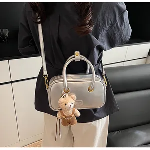 Silver mini square bag with metallic finish featuring a cute teddy bear charm on the handle