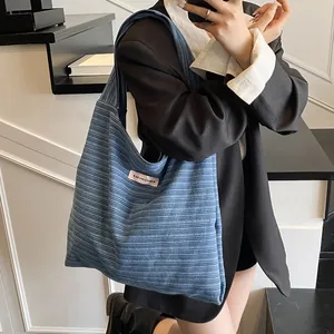 Light blue striped canvas tote bag with a small pink label shown on a female model