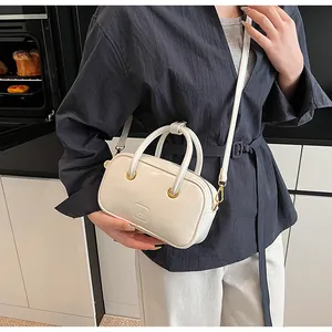 White leather handbag with gold hardware shown on model in a modern interior setting