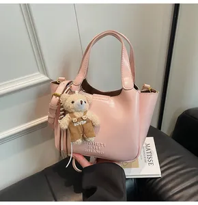 Rosafarbene glänzende Beuteltasche mit Plüschbären-Anhänger und geprägtem Schriftzug