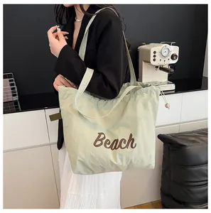 Primer plano del bolso tote de nailon verde claro con texto Beach y cordón ajustable