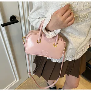 Chic pink patent leather small square bag with gold hardware worn as a crossbody purse