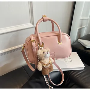 Detailed view of pink mini Boston bag with faux leather texture and plush bear charm