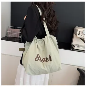 Detalle del bolso tote de nailon verde claro con estampado Beach y cierre ajustable