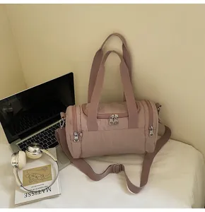 Detailed view of pink nylon cylinder sports bag with adjustable strap and dual zipper