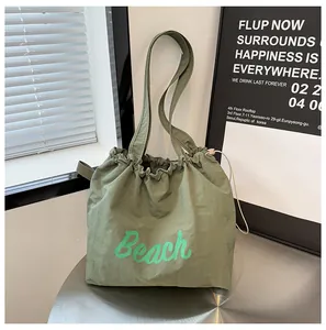 Detalle de bolsa tote de nailon verde oliva con cordón e impresión de letras Beach