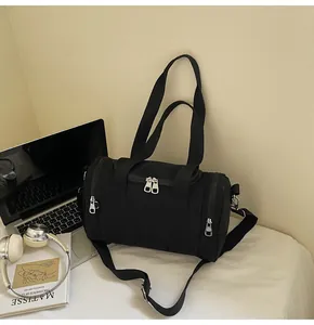 Detail of black cylindrical nylon shoulder bag with silver hardware and adjustable strap
