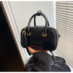 Close-up of black glossy leather handbag with golden hardware and brand engraving