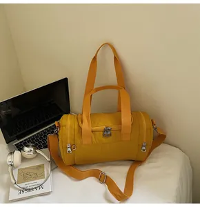 Detail of yellow nylon cylindrical gym bag featuring metal zippers and detachable strap