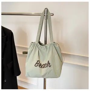 Detalle del bolso tote de nailon verde pálido con cordón y estampado Beach