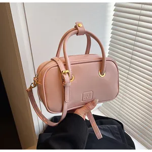 Detail of pink faux leather crossbody bag with brand logo embossing and gold hardware
