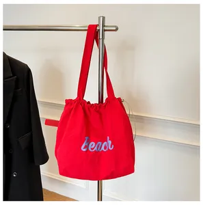 Detalle de bolso tote de lona roja con estampado Beach colgado en un soporte