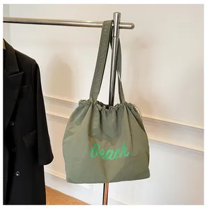 Detalle del bolso tote de nailon verde oscuro con cordón e impresión de letras Beach