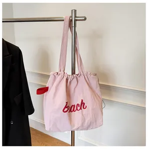 Detalle del bolso tote de nailon rosa claro con letras Bach rojas y cierre de cordón