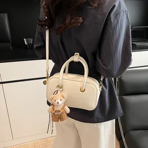 Fashionable cream white leather crossbody bag with cute plush bear charm on model