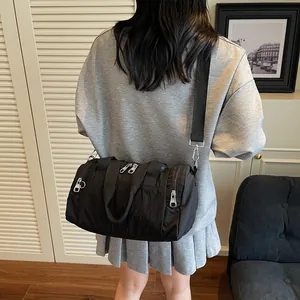 Minimalist black nylon barrel shoulder bag for women with wide adjustable fabric strap