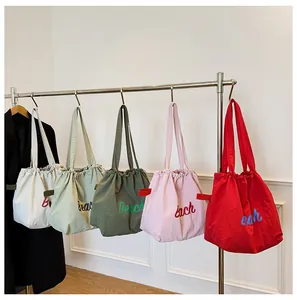 Detalle de bolsos de nailon coloridos con cierre de cordón y estampado Beach