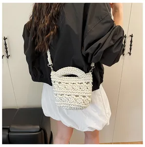 Detail der handgewebten cremefarbenen Mini-Beuteltasche mit Lochmuster und Gurt