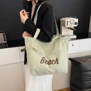 Bolso tote de lona verde claro con estampado Beach marrón y cordón mostrado en modelo