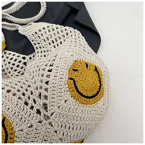 Detail of hand-woven off-white straw tote bag featuring a bright yellow smiley face