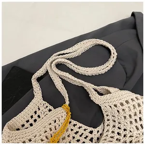 Detail of hand-woven straw tote bag with beige crochet pattern and yellow stitching