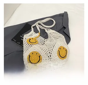 Detailed close-up of handmade white crochet tote bag with yellow smiley face patch