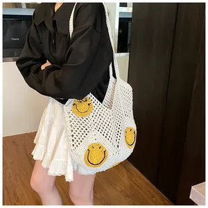 Detail of white crochet tote bag with yellow smiley face patches and hollow mesh texture