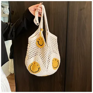 Detail of hand-crocheted cream tote bag featuring three yellow smiley faces on mesh fabric