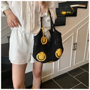 Close-up of black crochet tote bag with yellow smiley face pattern and matching charm