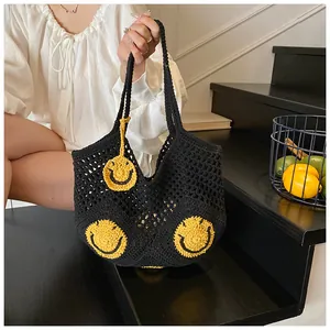 Detail of hand-woven black mesh beach tote bag featuring yellow smiley face patches