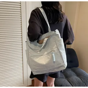 Dettaglio della borsa tote in nylon azzurro con tasca a zip e tirante intrecciato